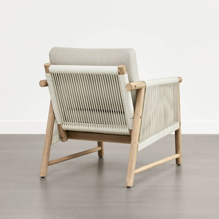 A Sienna Modern Acacia wood woven outdoor lounge chair with light beige cushions, viewed from the back.