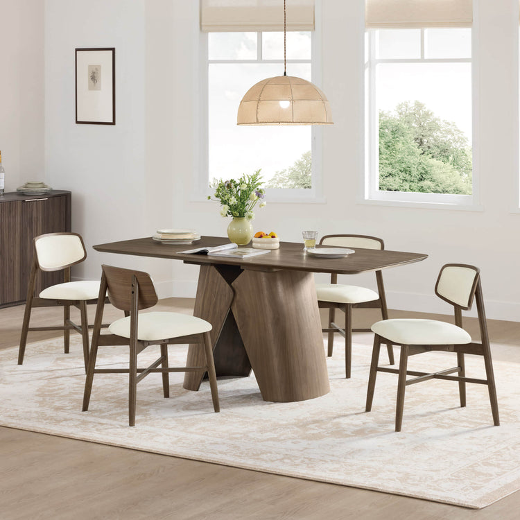 Elowen walnut dining table with sculptural wood pedestal base and cream chairs.