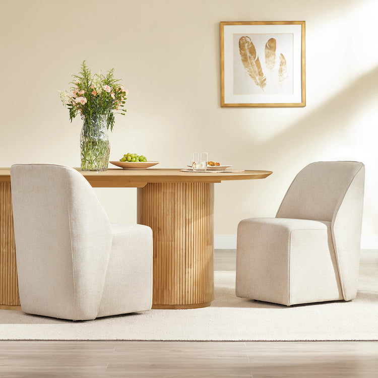 Two light neutral upholstered Soren rolling dining chairs with casters around a fluted wood table.