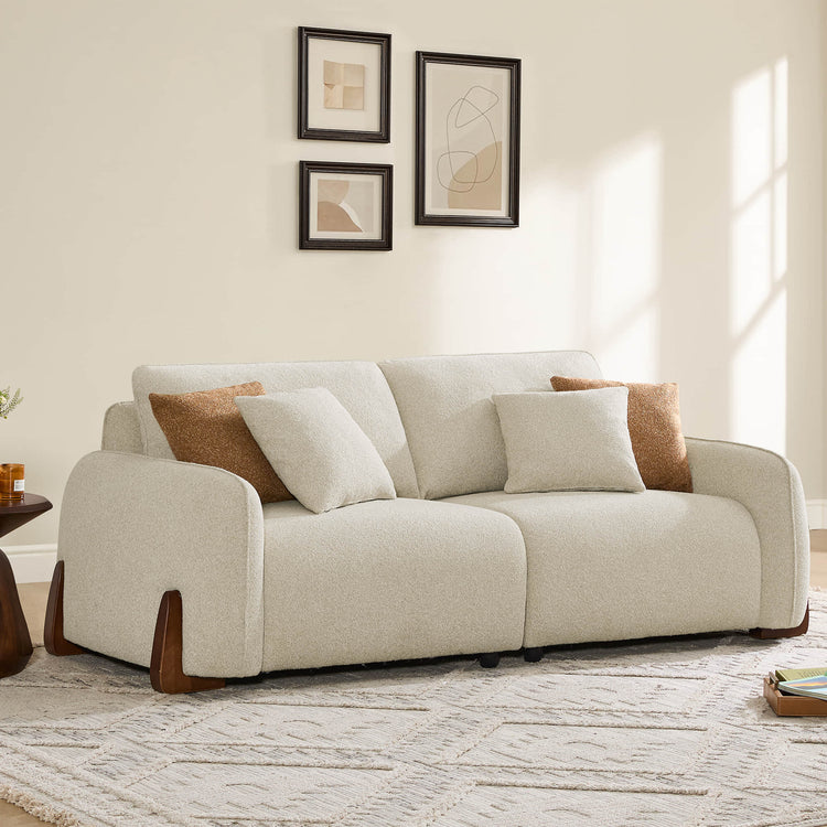 Teleri 2-seat modular curved sofa in cream bouclé fabric with angled wood legs and accent pillows.