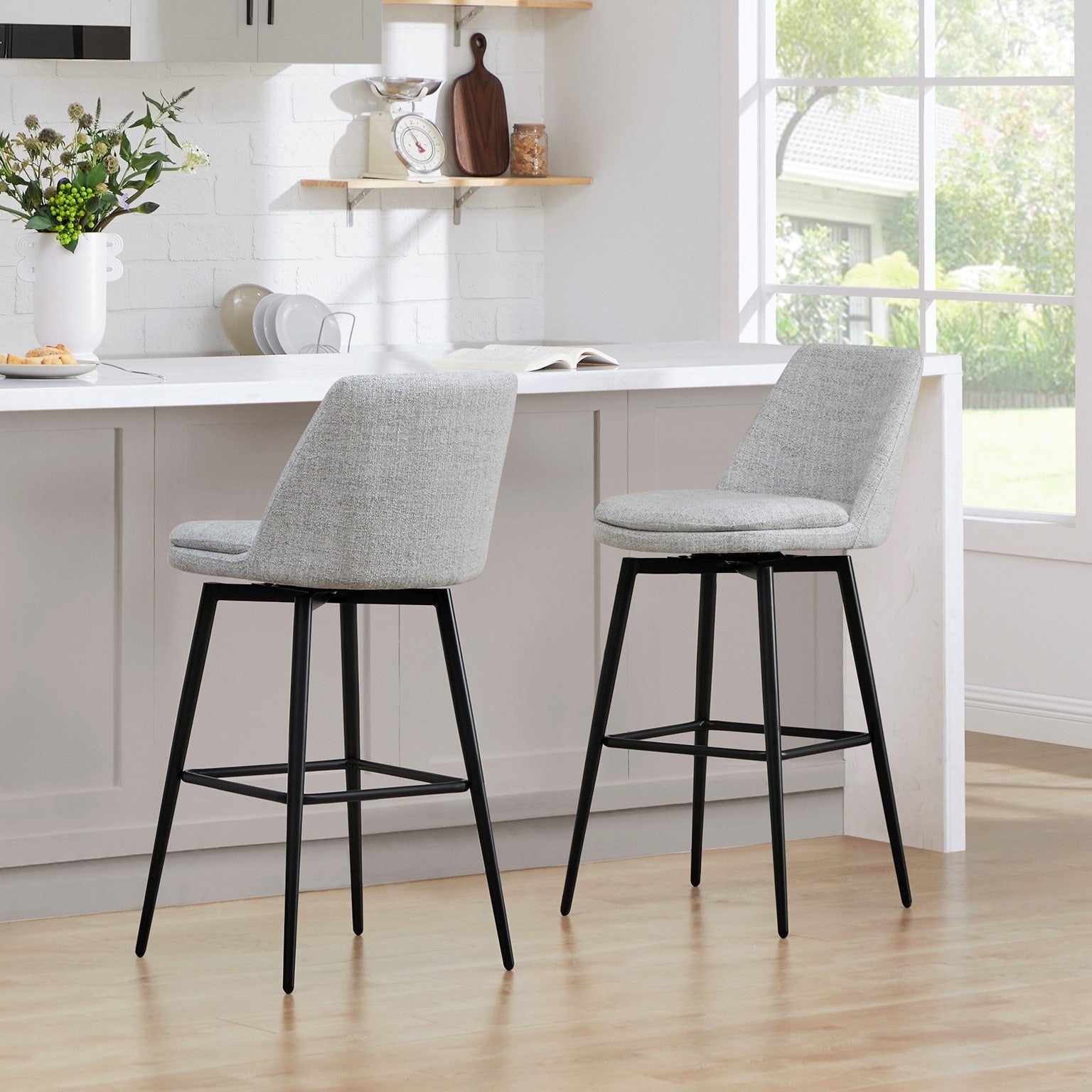 Eli swivel bar stools with light gray fabric seats and black metal frames in a bright kitchen - CHITA Living