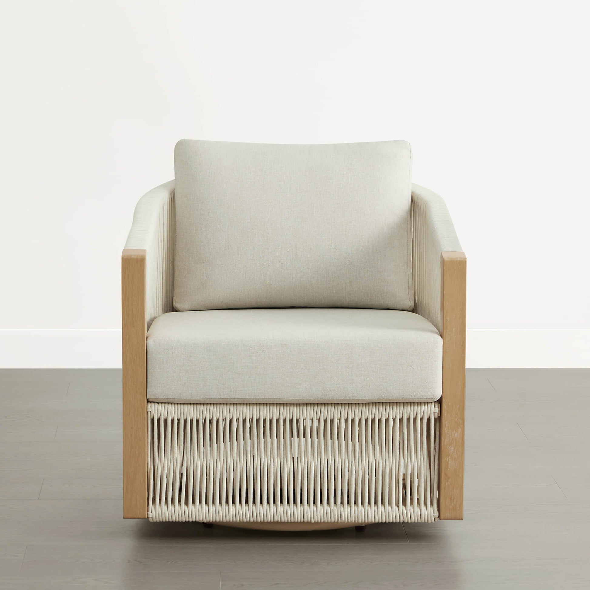 A woven outdoor swivel lounge chair with light wood frame and cream cushions.