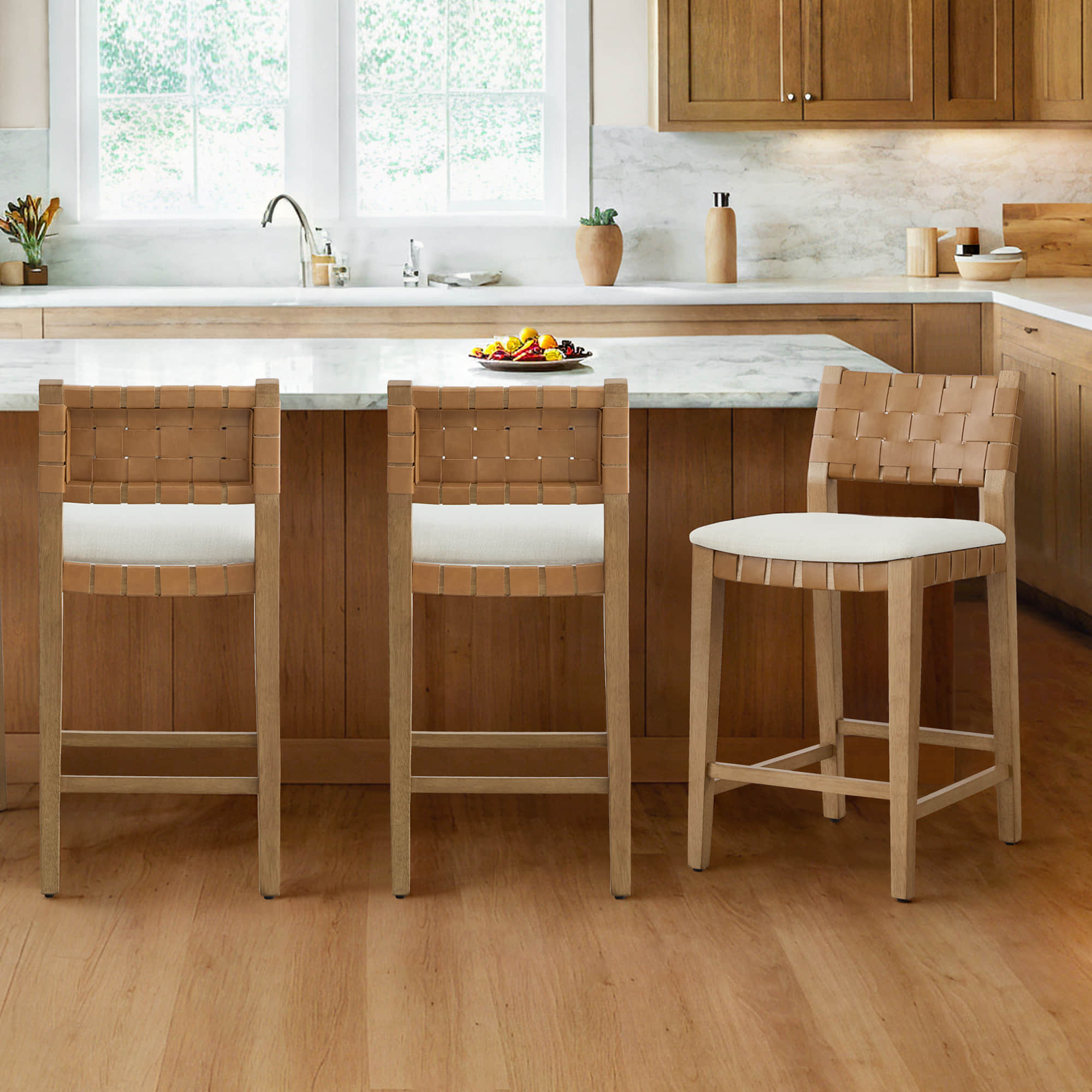 Aries Mid-century Modern Handwoven Counter Stools with woven leather backs and white cushions, arranged around a kitchen island.