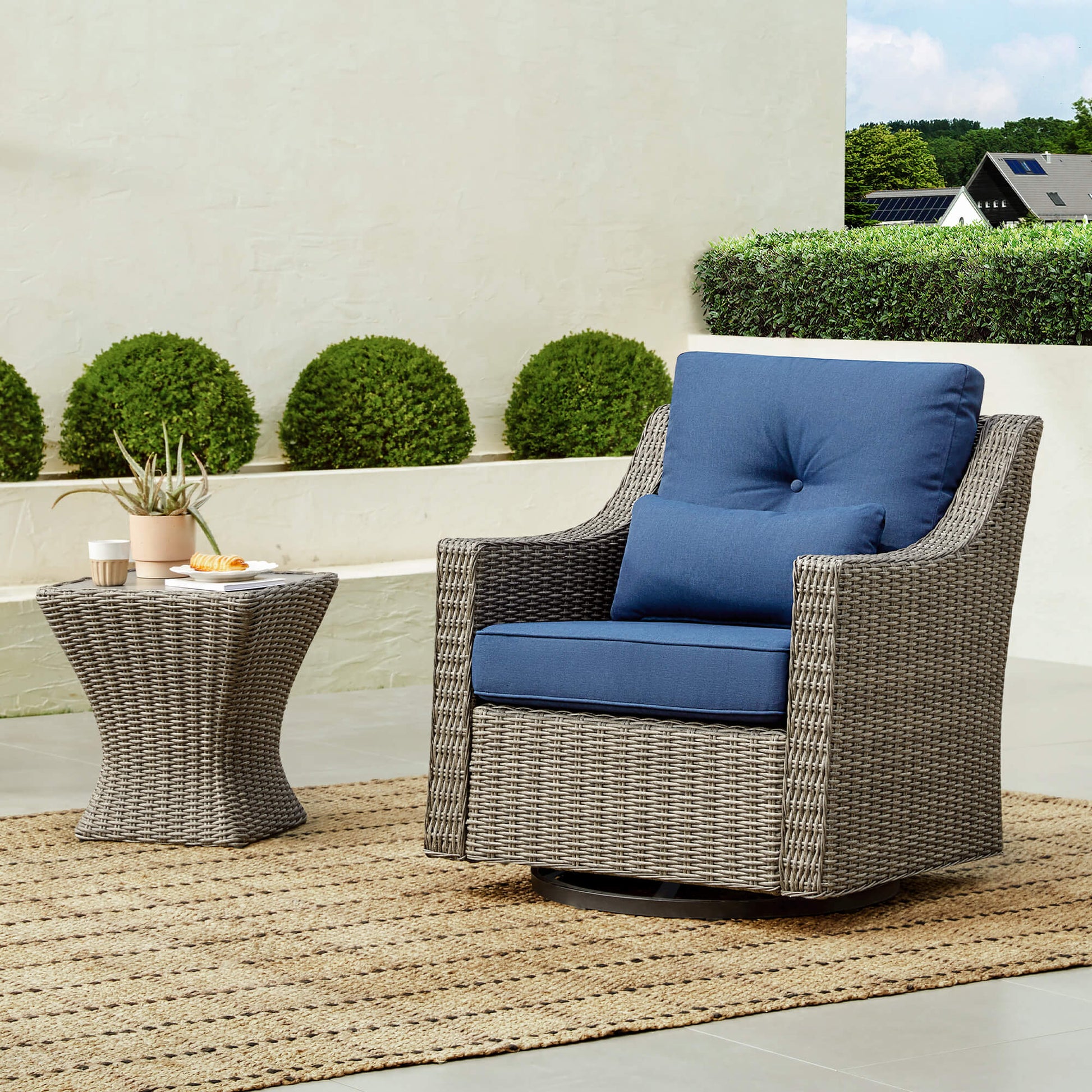 Elara Rattan Outdoor Chair with navy blue cushions and woven side table on a patio - CHITA Living
