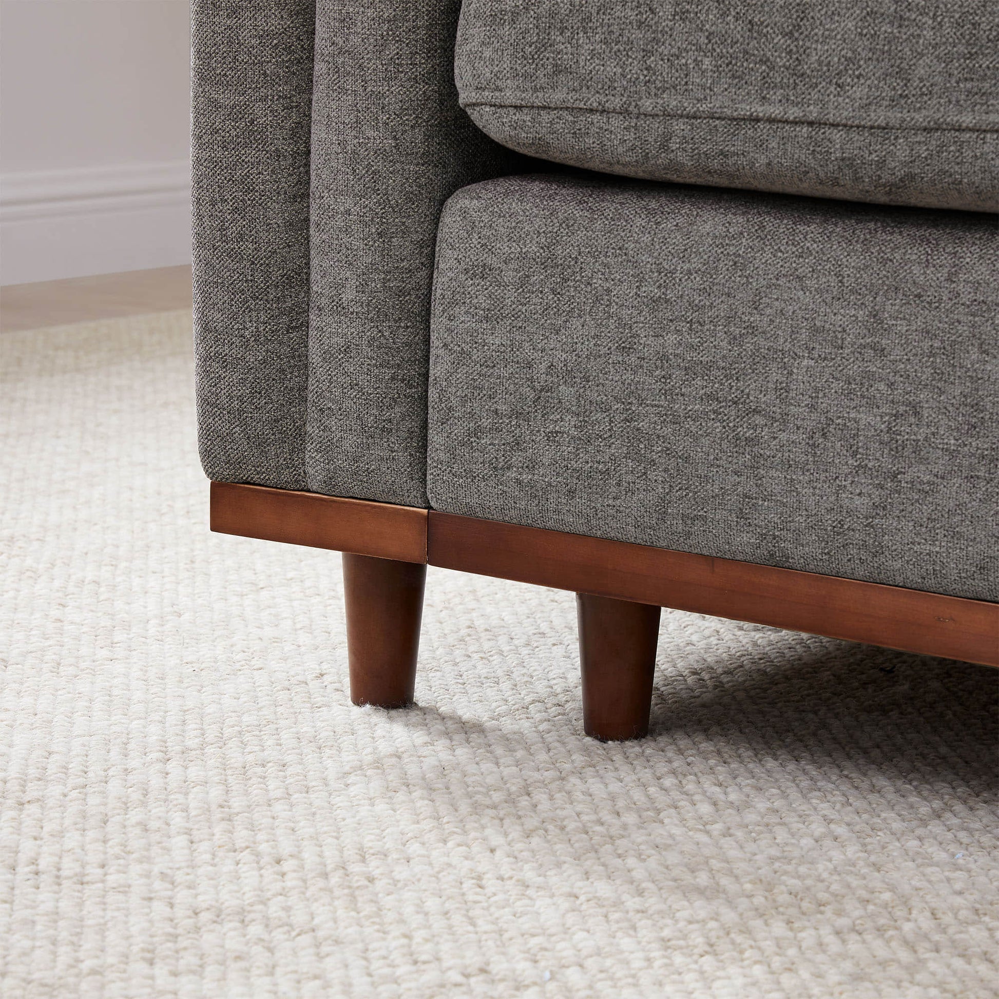 Close-up of Liam Modular Sofa’s wood base and gray fabric cushion in modern setting - CHITA Living
