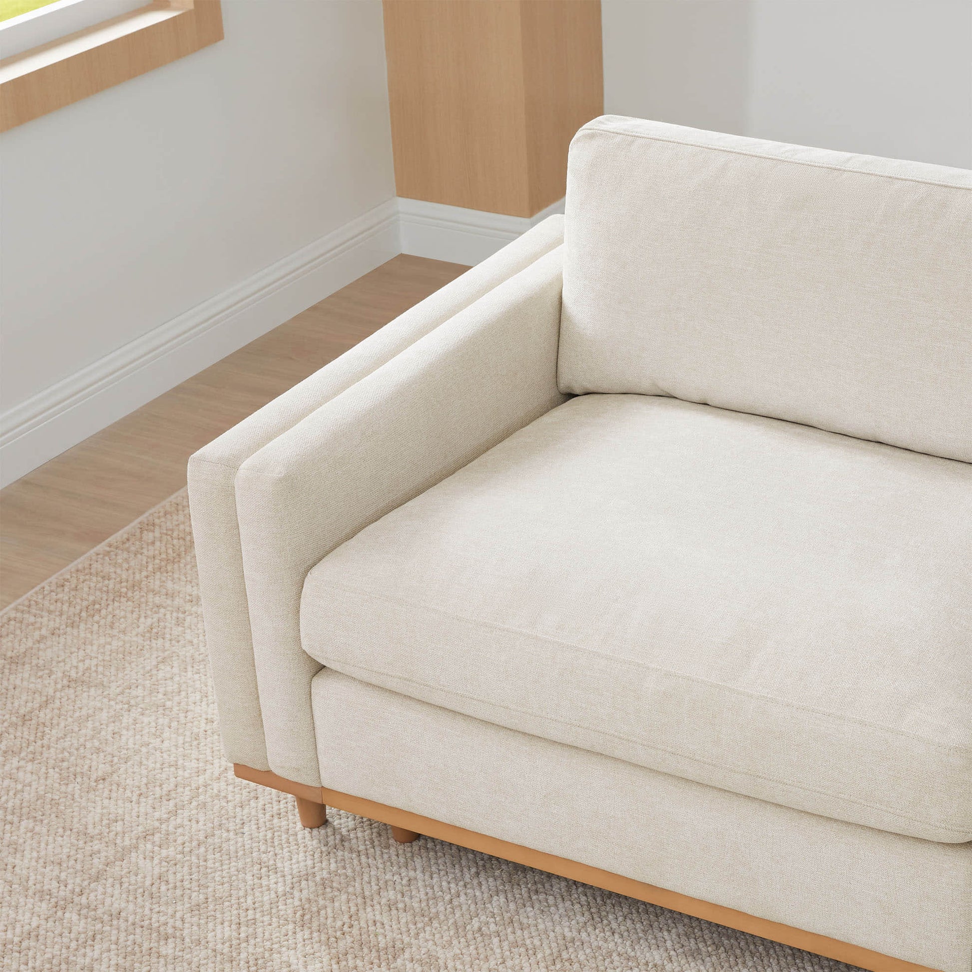 Close-up of Liam Sectional sofa cushion and wooden base in bright living room - CHITA Living