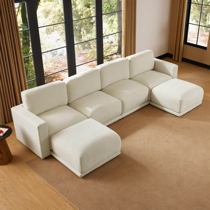 Aerial view of a modern sectional sofa with a minimalist design, set in a cozy room with large windows and a natural color palette.