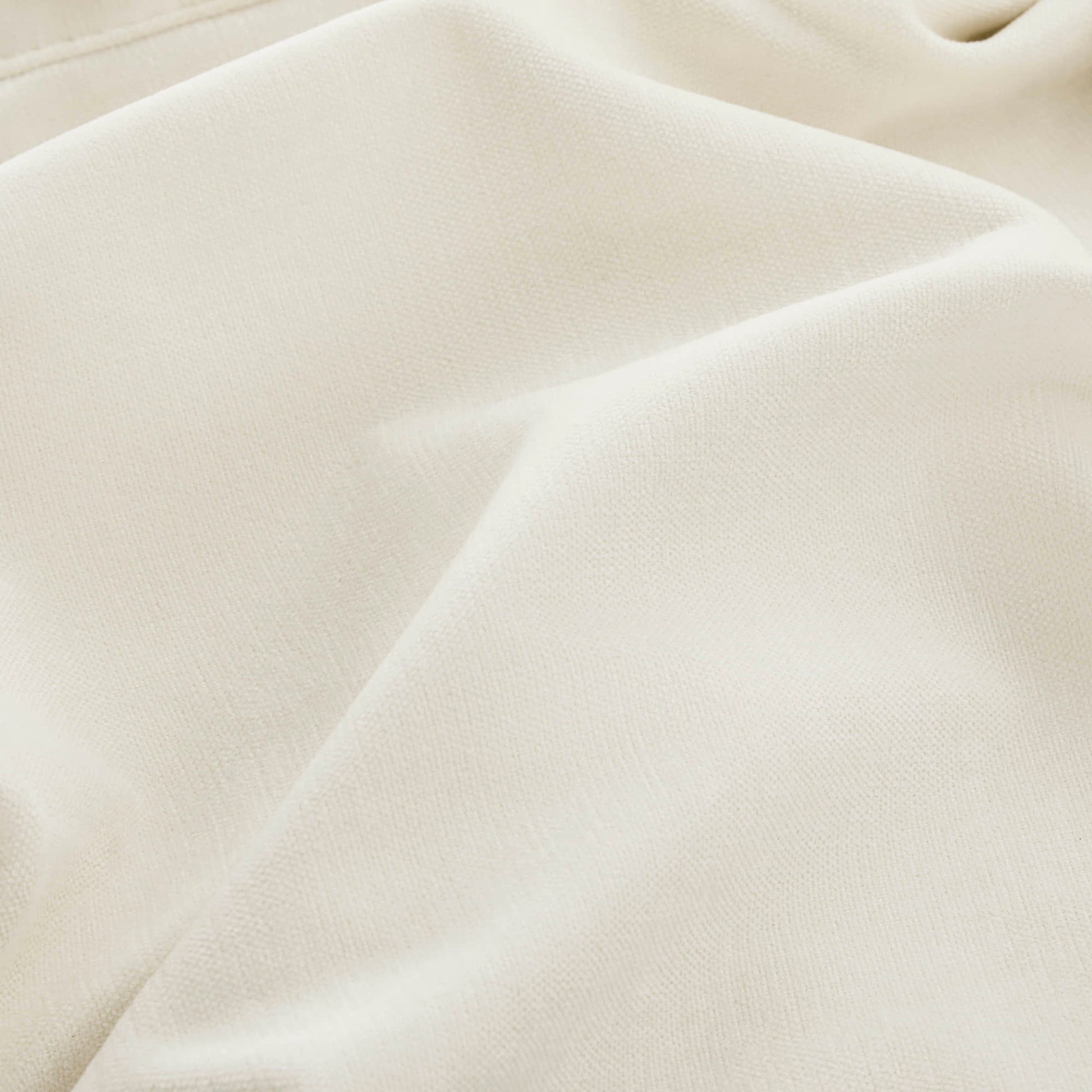 A close-up of a beige fabric with a small blue dot, highlighting the texture and folds.