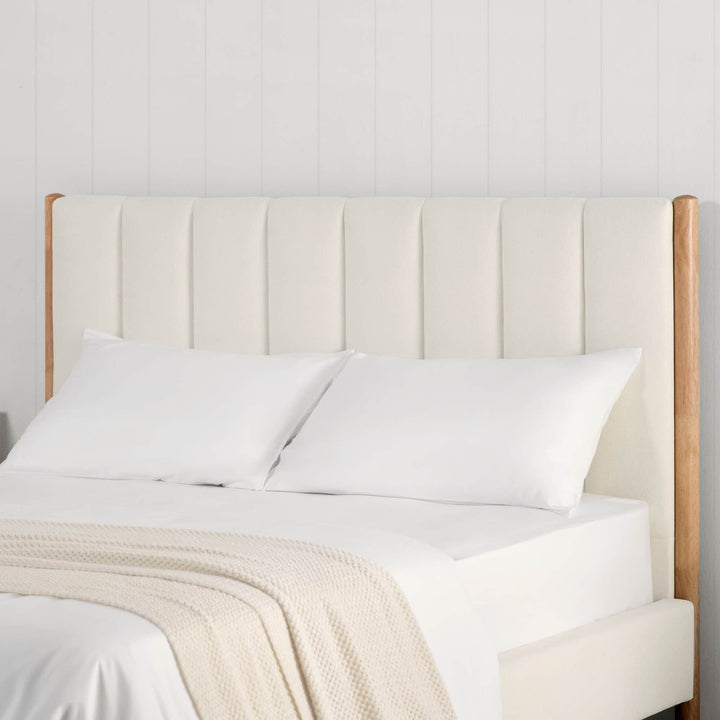 Serene upholstered bed headboard in cream fabric with wooden sides in a bright room - CHITA Living