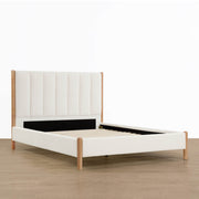 Cream queen-size bed with light wood legs and modern design in spacious room - CHITA Living