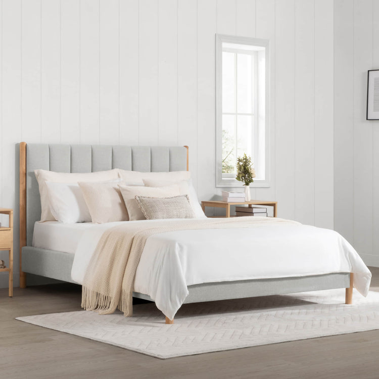 Serene queen-size bed with gray upholstery and light wood frame in bright, modern bedroom - CHITA Living
