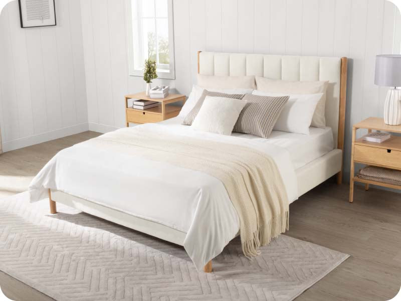 Serene queen-size bed with neutral bedding and light wood nightstands in bright room - CHITA Living