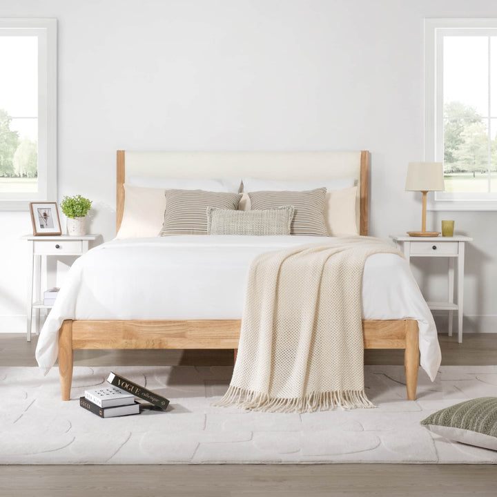 Solid wood bed with light fabric headboard and cozy bedding in a bright room - CHITA Living