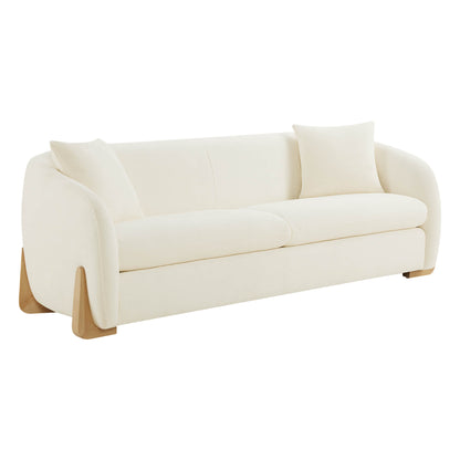 Modern sofa with curved design, cream upholstery, and wooden legs