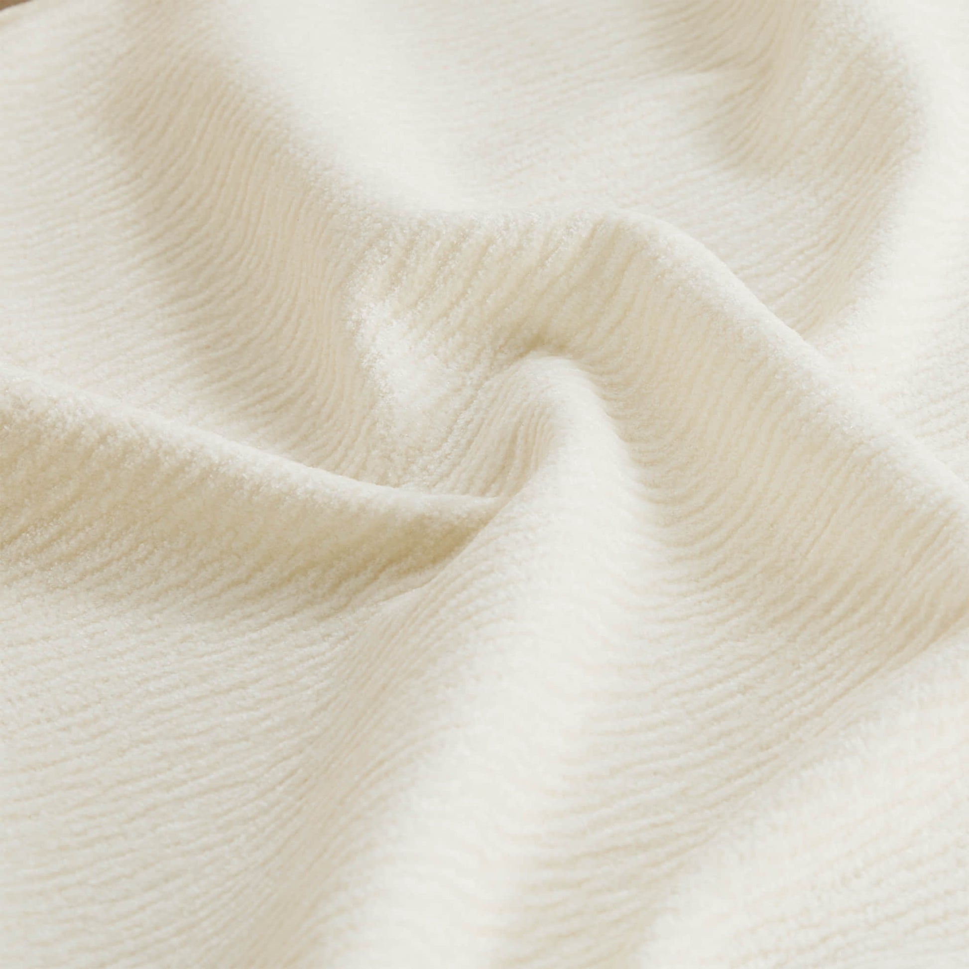 Close-up view of cream fabric with a soft, textured surface and gentle folds.