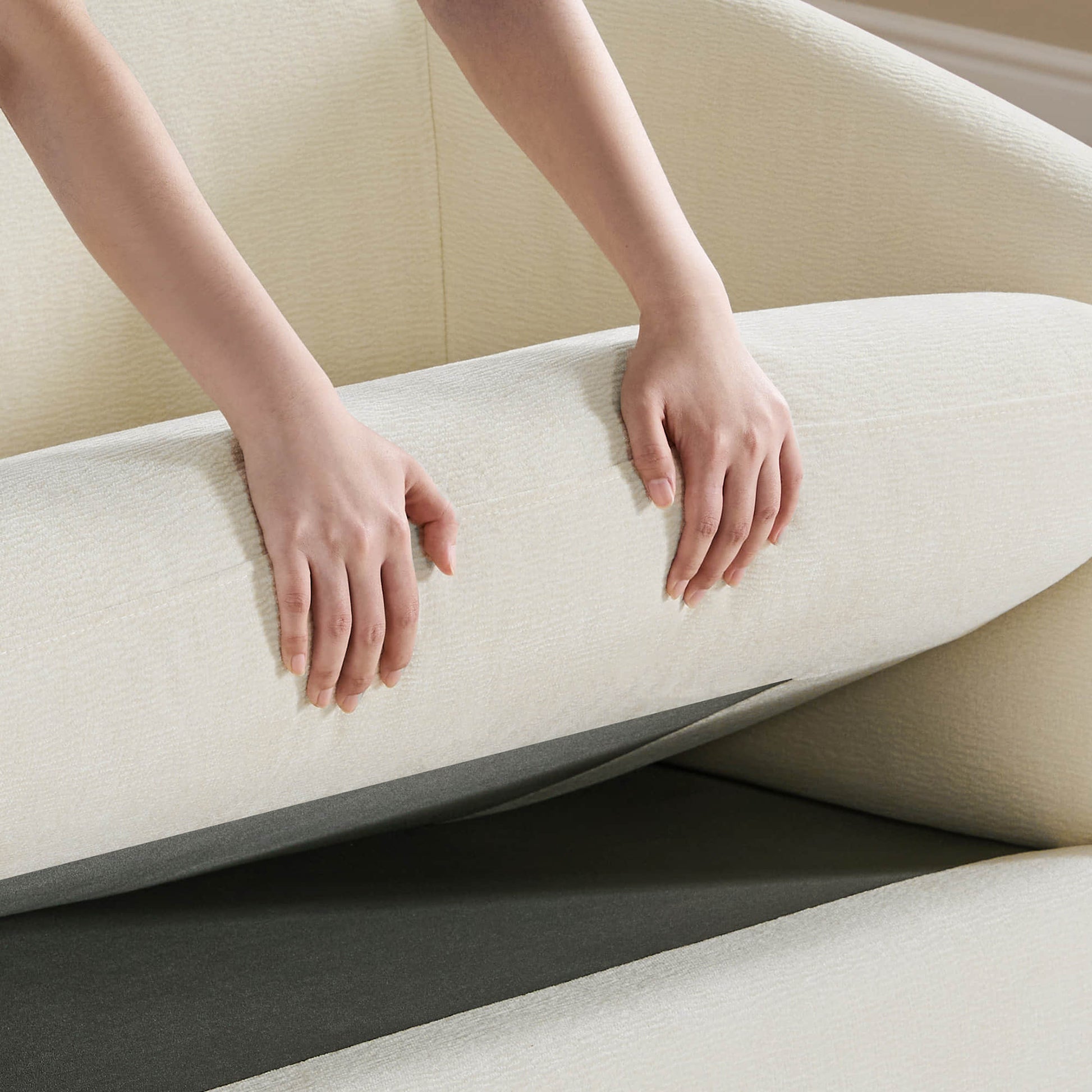 Hands adjusting a modern sofa cushion, showcasing comfort and versatility in wood sofas.