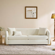 Cream modern sofa with wooden accents, elegantly placed in a cozy living room setting.