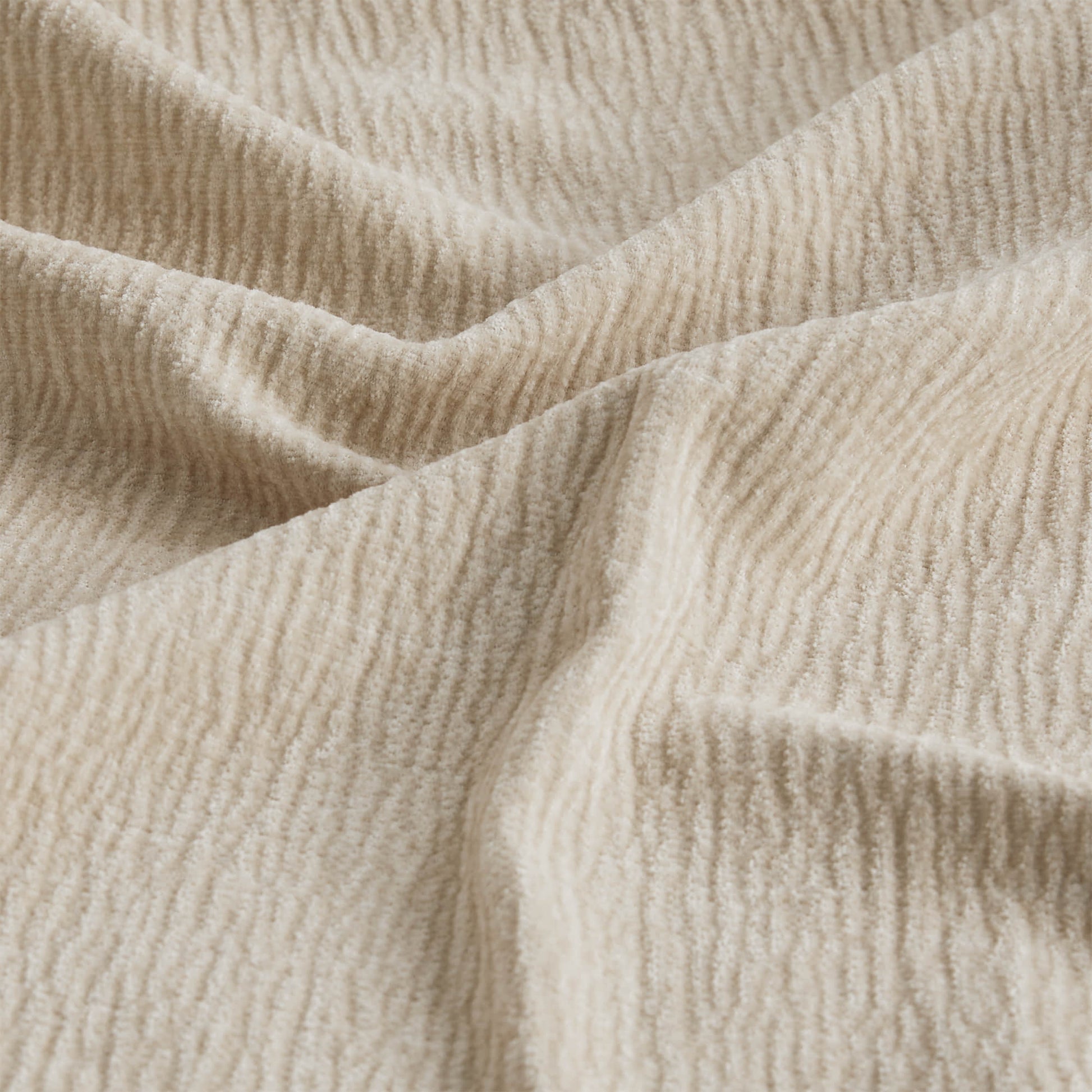 Close-up of a textured cream fabric with a soft, wavy pattern.