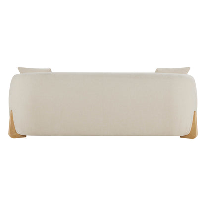 Rear view of a modern cream sofa with a smooth, rounded design and wooden legs, showing two cushions peeking over the backrest.