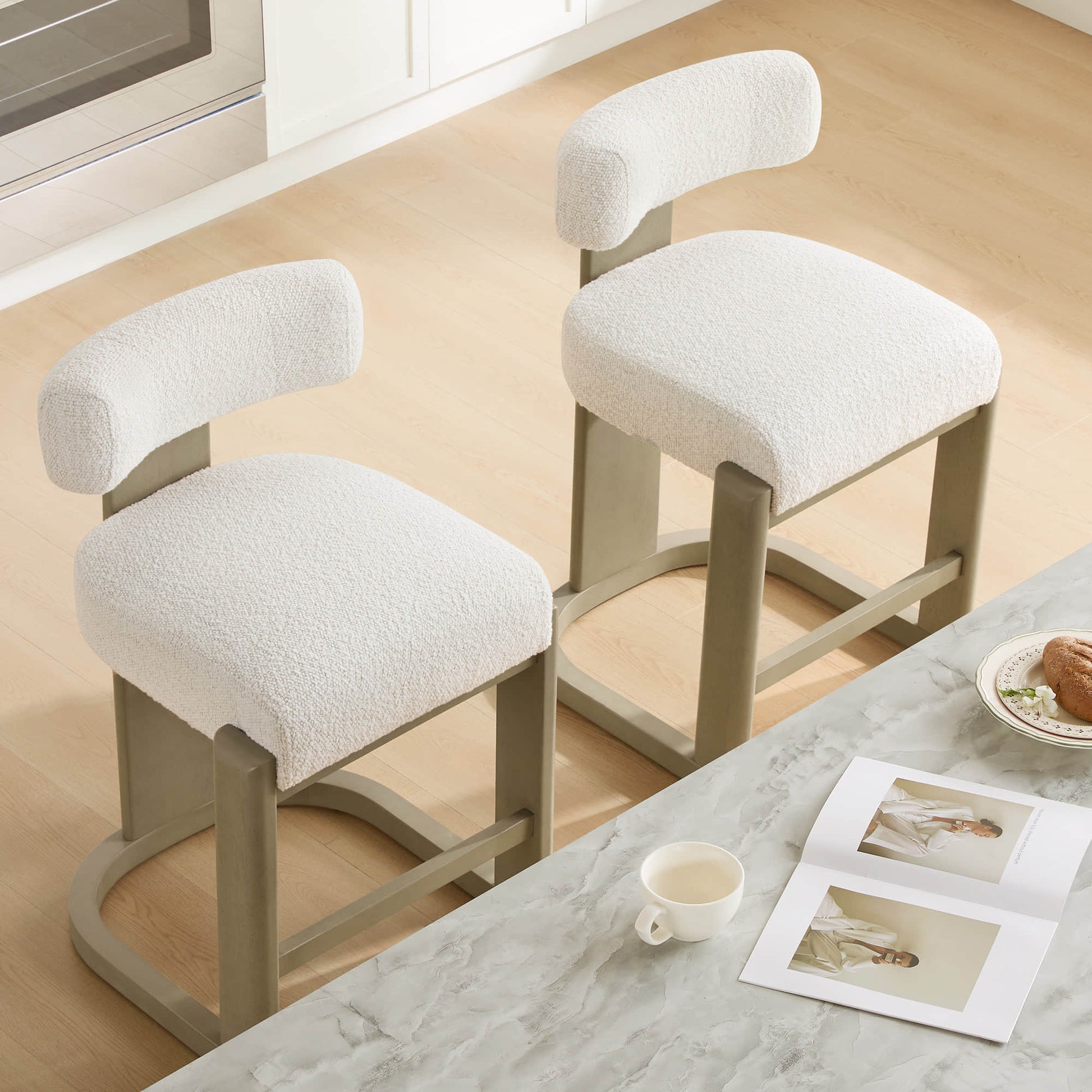 Troy Boucle Counter Stools with solid wood frames and cream bouclé upholstery offer a stylish, modern seating option.