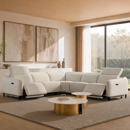 A modern white sectional sofa with reclining seats, styled in a bright, contemporary living room with gold coffee tables, a beige rug, and large abstract wall art.