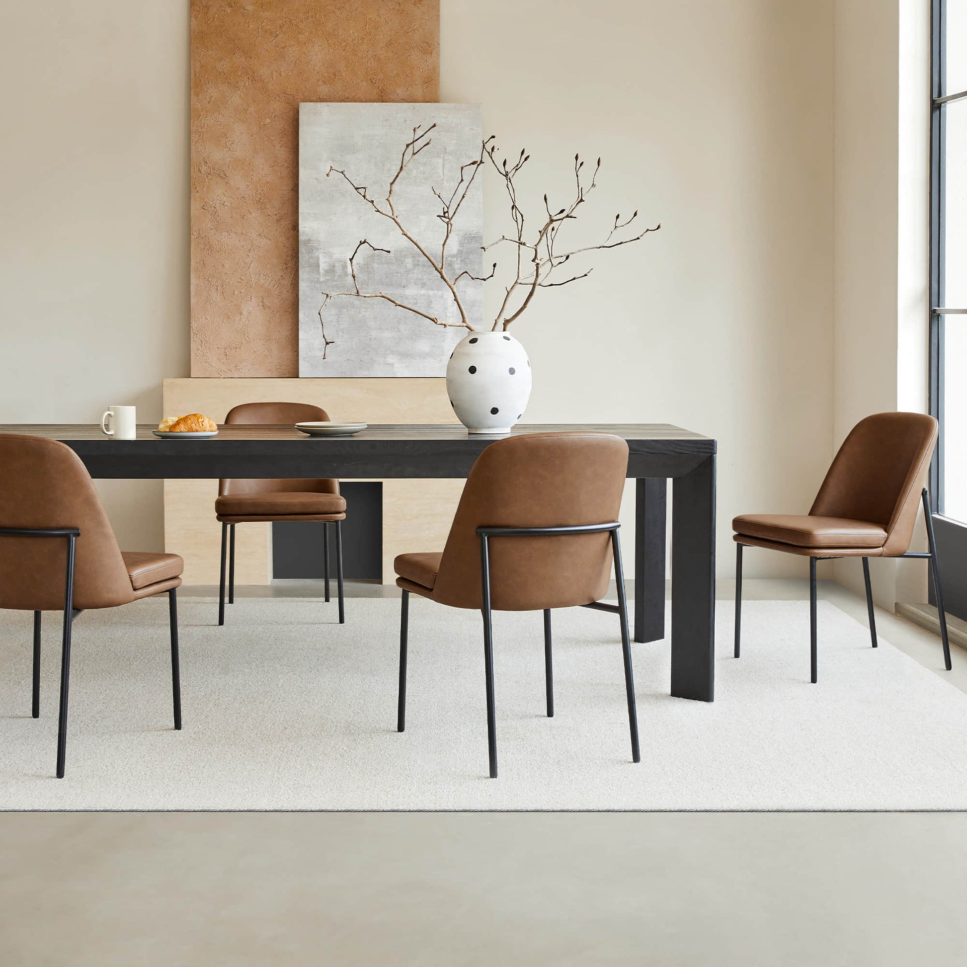 Golda Dining Chair, brown leather with black metal legs, set around a modern dining table in a stylish room.