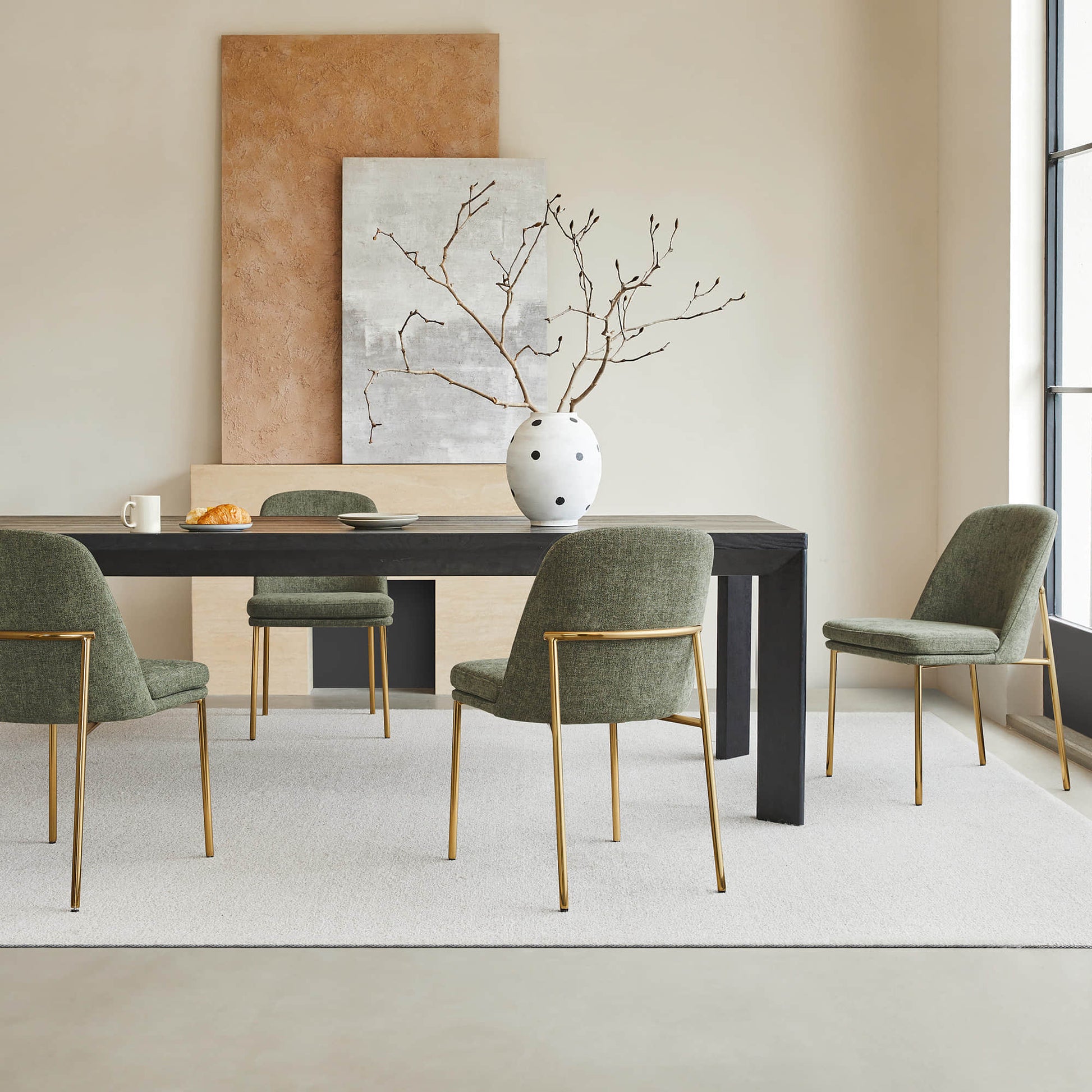 Golda Dining Chair, green fabric with gold legs, set around a modern dining table in a bright room.