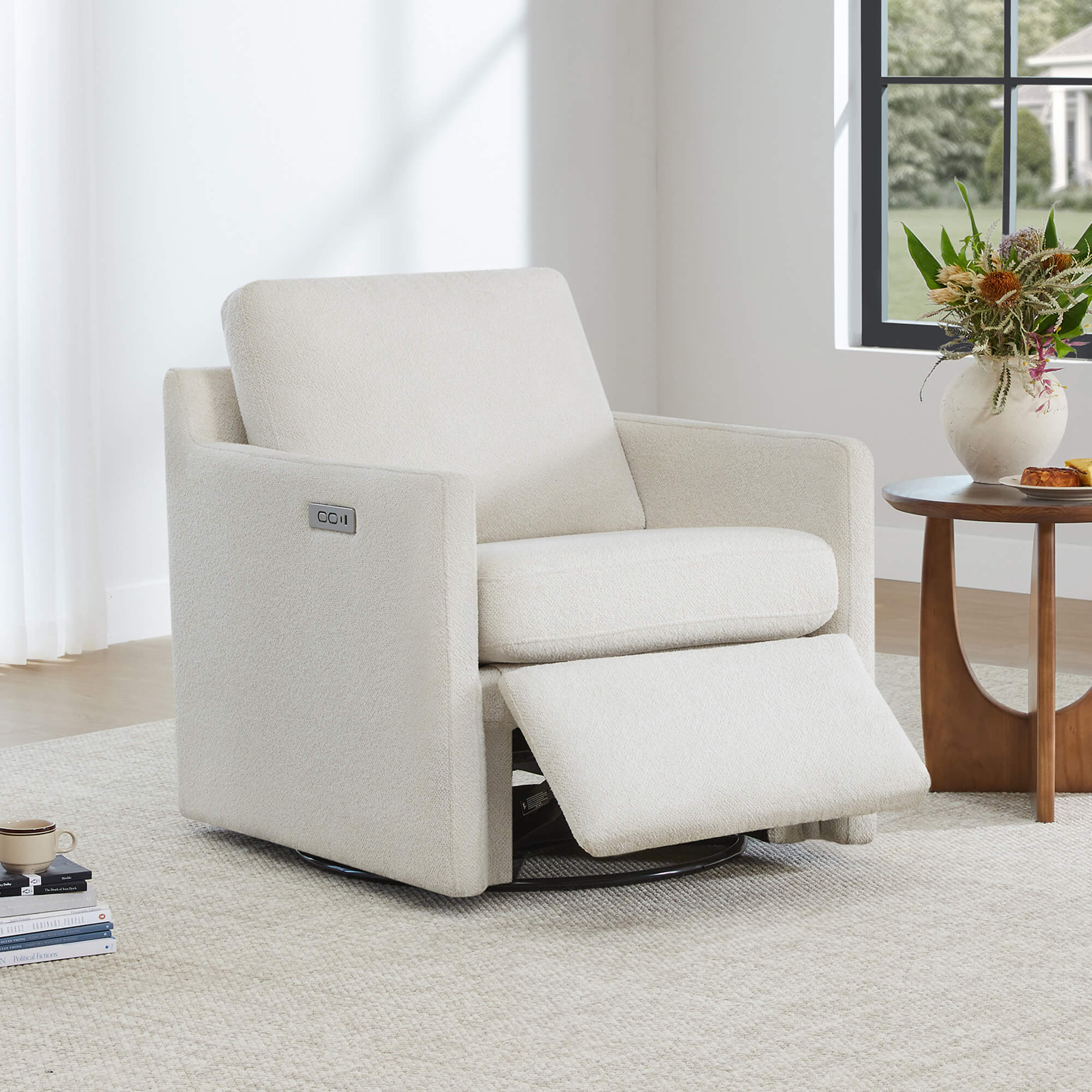 Henry Power Swivel Recliner in light beige fabric, footrest extended, next to a side table with a vase of flowers.