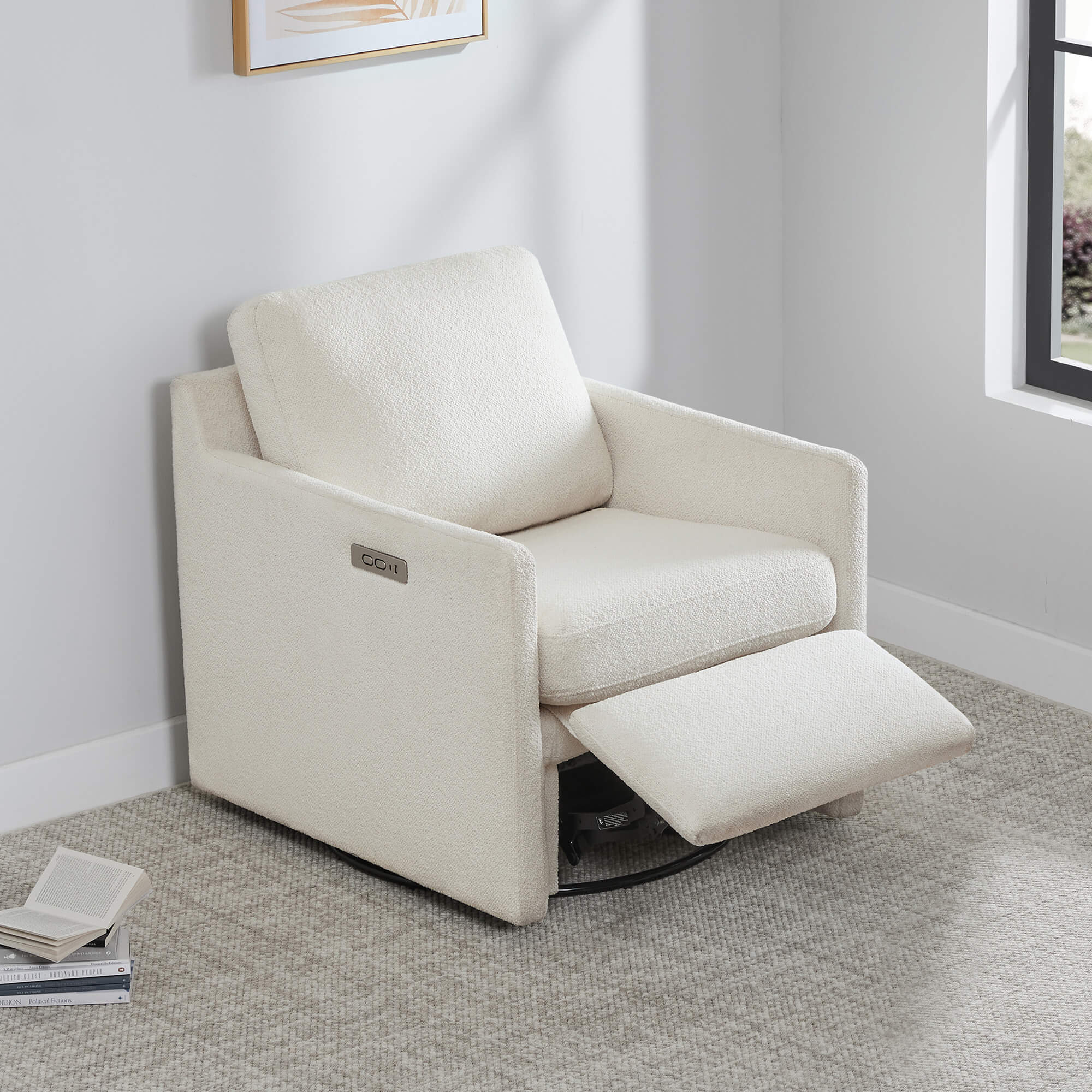 Henry Power Swivel Recliner in light beige fabric, footrest extended, next to a stack of books.