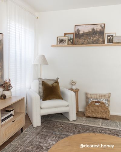 A cozy corner with a white armchair, a floor lamp, a wooden side table
