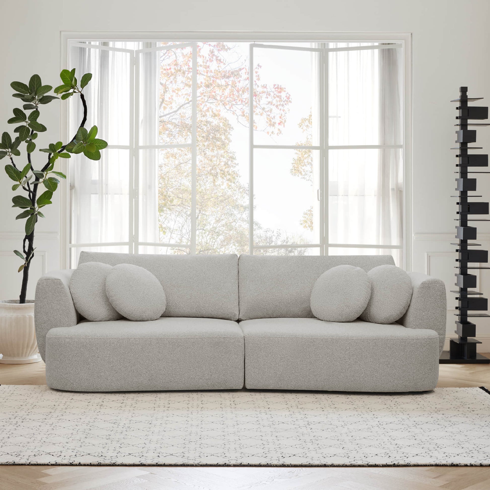 Grace curved gray sofa with round cushions in a sunlit modern living room - CHITA Living