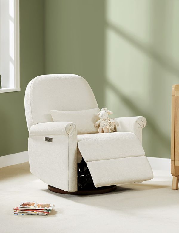 A white recliner with a plush sheep toy on it, next to a window with soft light.