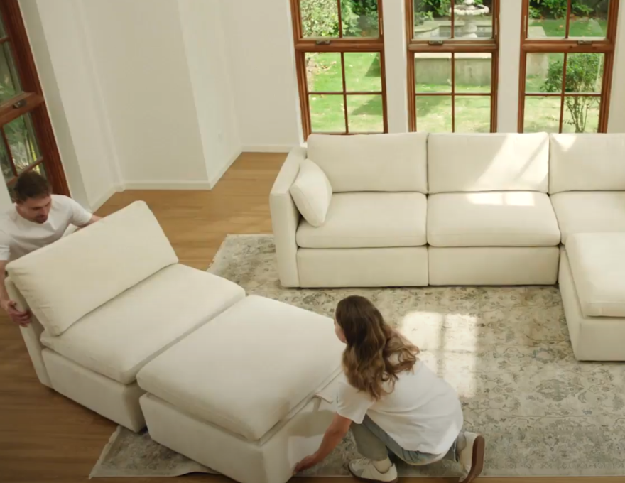 A man and woman assembling a white sectional sofa in a bright