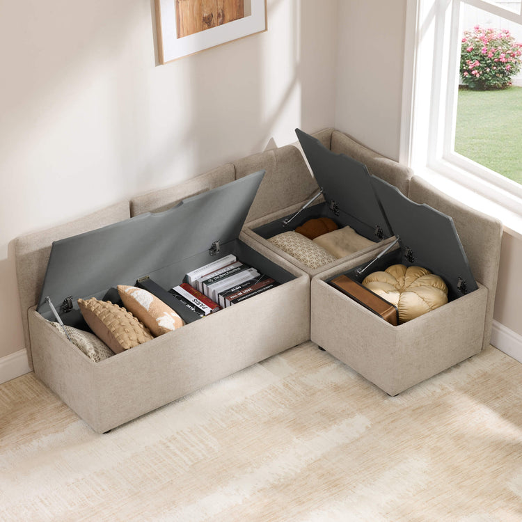 Lila L-shaped banquette with storage in beige fabric, showing open lids revealing storage for books and blankets.