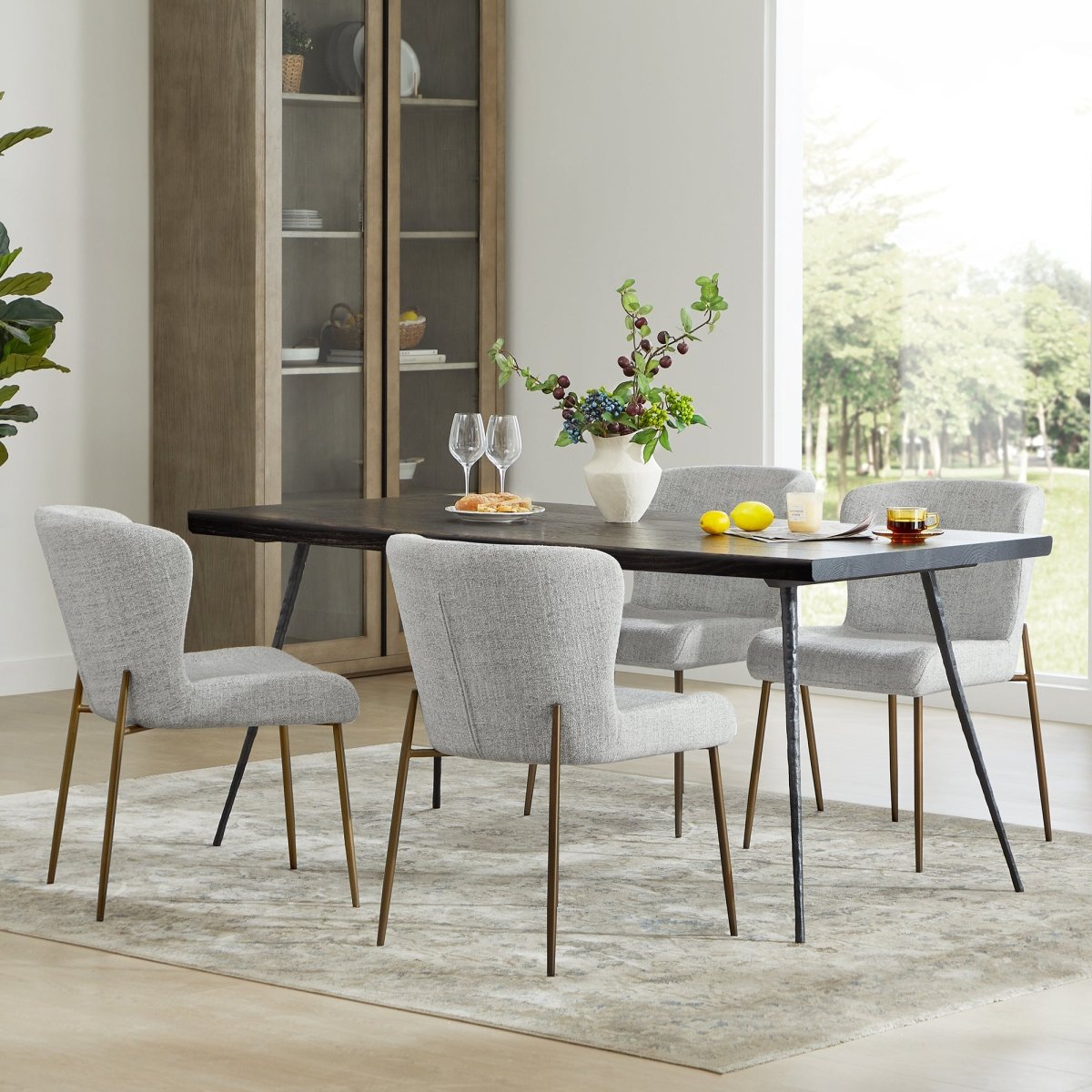 Golda Dining Chairs in grey fabric around a dark wood dining table in a bright room - CHITA Living