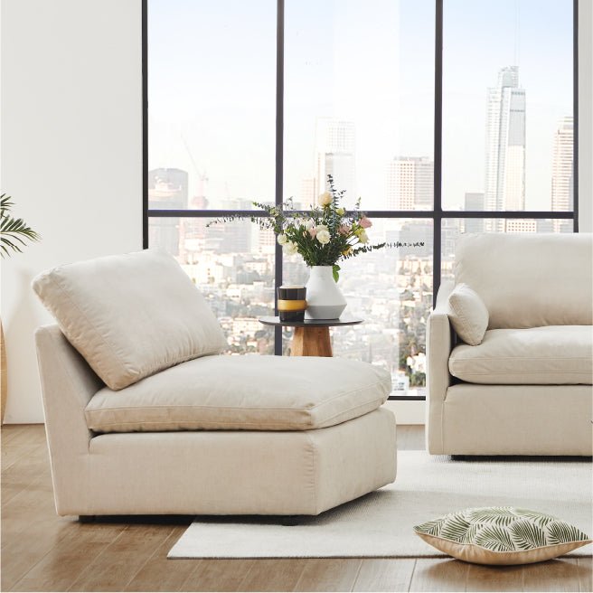 Kenna Armless Chair and Ottoman in a modern living room, light fabric, comfortable seating, and city view